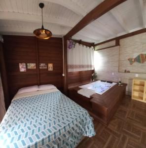 a bedroom with a bed and a tub in it at pimenta rosa guesthouse in Praia do Rosa