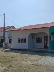 een wit gebouw met een rood dak bij EMBUN 2 LANGKAWI HOMESTAY in Pantai Cenang