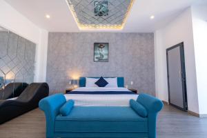 um quarto com uma cama azul e um sofá em Joi Hospitality - Front Beach em Vung Tau