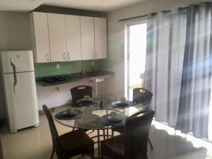 Una cocina con mesa y sillas y un refrigerador. en Villa das Flores - aptos 2 e 9, en Pinheira