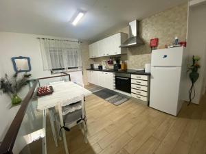 a kitchen with a table and a white refrigerator at Ninho D'Arara in Tondela