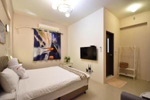a bedroom with a white bed and a tv at Piau Po 21 Inn in Taitung City
