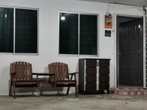 two chairs sitting in front of a building with windows at VIRTA Guesthouse in Sandakan