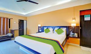 a bedroom with a large white bed with green pillows at Treebo Trend Vhyomaan Resort in Mahabaleshwar