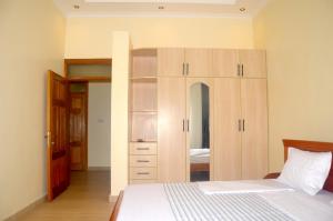- une chambre avec un lit et une grande armoire en bois dans l'établissement Sunny Hill Apartments, à Kigali