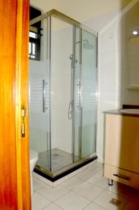 La salle de bains est pourvue d'une douche en verre et de toilettes. dans l'établissement Sunny Hill Apartments, à Kigali