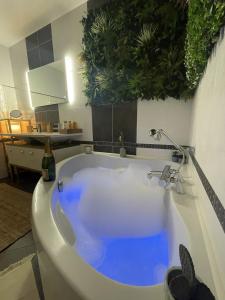 El baño incluye bañera blanca con agua azul. en Cosy et jardin panoramique, en Morlaix