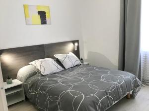 - une chambre avec un grand lit et une couette grise dans l'établissement Appartement Lumea 80 m2 climatisé parking proche Sanctuaires, à Lourdes