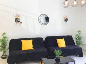 a living room with two black couches and yellow pillows at Appartement Lumea 80 m2 climatisé parking proche Sanctuaires in Lourdes