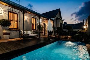 una piscina frente a una casa por la noche en 84 on Fourth Guest House en Johannesburgo