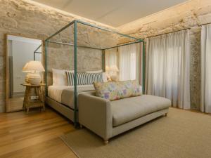 1 dormitorio con cama con dosel y sofá en Saboaria Boutique Hotel Porto, en Oporto