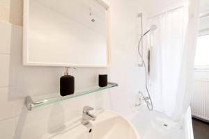 W białej łazience znajduje się umywalka i lustro. w obiekcie Cozy Apartment ° 7 beds ° 3 bed rooms w mieście Kleve