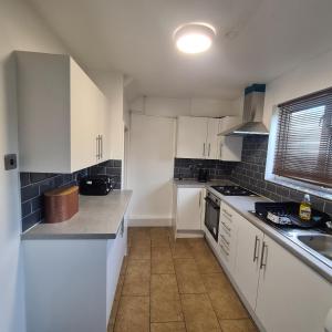 a white kitchen with white cabinets and a sink at Lovely Home away from home! in Bexleyheath