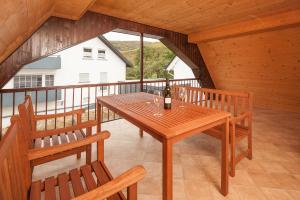 y balcón con mesa y sillas de madera. en Ferienwohnung Pfaffenweiler, en Pfaffenweiler