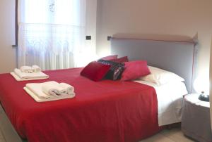 Una cama roja y blanca con toallas encima. en Palazzo del Duca, en Verona