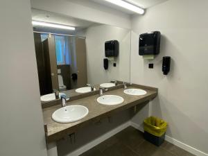 łazienka z 3 umywalkami i dużym lustrem w obiekcie Zarautz Surf House w mieście Zarautz