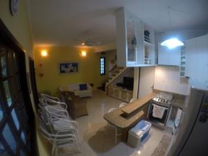 a kitchen and living room with white chairs in a room at Chalé Recanto do Barão in Boicucanga