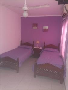 2 camas en una habitación con paredes moradas en CONFORTABLE DUPLEX CON GARAGE en Santiago del Estero