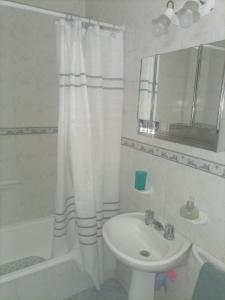 Baño blanco con lavabo y cortina de ducha en CONFORTABLE DUPLEX CON GARAGE en Santiago del Estero