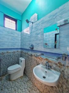 a bathroom with a sink and a toilet and a mirror at Tathāgata Homestay in Lumbini