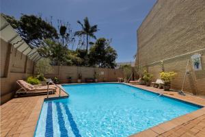 a swimming pool in a backyard with a brick wall at Umhlanga Beach 3 Bedroom Apartment in Durban
