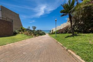a brick road with a palm tree and a street light at Umhlanga Beach 3 Bedroom Apartment in Durban