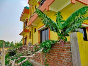 ein gelbes Haus mit einer Palme davor in der Unterkunft Tathāgata Homestay in Rummindei