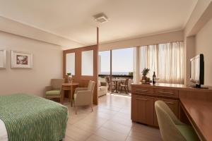 une chambre d'hôtel avec un lit et un salon dans l'établissement Atlantica Oasis Hotel, à Limassol