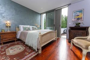 a bedroom with a bed and a chair and a window at Golf Course - Luxurious Flat T3 - Ponte de Lima in Ponte de Lima