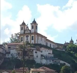 a church on top of a hill with houses at Imperdível - Casa aconchegante com varanda in Ouro Preto
