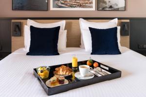 a tray of food on a bed with a breakfast at Golden Tulip Villa Massalia in Marseille