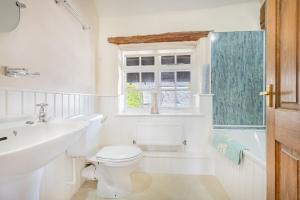 a bathroom with a toilet and a sink and a window at farmhouse cottage in Keswick