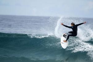 a man riding a wave on a surfboard in the ocean at Apartamentos Nautilus in Bajamar