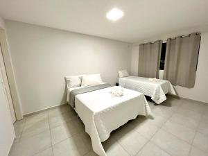 1 dormitorio con 2 camas y ropa de cama blanca. en Casa em Porto de Galinhas by AFT en Porto De Galinhas
