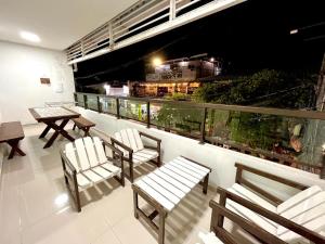 a balcony with chairs and tables on a building at Casa em Porto de Galinhas by AFT in Porto De Galinhas