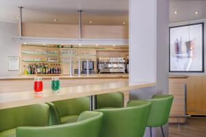 a bar in a restaurant with green chairs at Hôtel Ariane in Lourdes