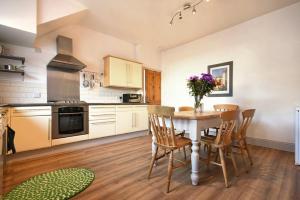 a kitchen with a table and chairs and a kitchen with white cabinets at Rosedale House in Amble