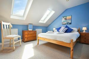 a bedroom with blue walls and a bed and a chair at Rosedale House in Amble