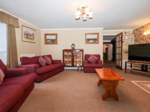 a living room with red couches and a flat screen tv at Twelve Oaks Farmhouse in Newton Abbot