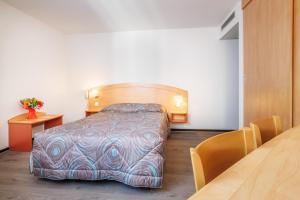 sypialnia z łóżkiem i stołem w pokoju w obiekcie Hôtel Ariane w Lourdes