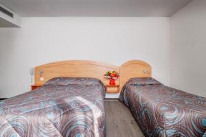 a bedroom with two beds and a table with flowers at Hôtel Ariane in Lourdes