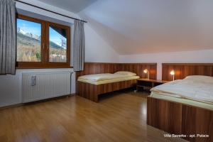 a bedroom with two beds and a large window at Apartmány Villa Severka in Vysoke Tatry - Novy Smokovec