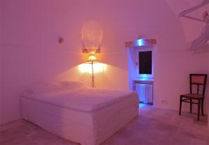 a white bedroom with a bed and a chair at Casa Antica Pietra Bianca in Ostuni