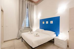 Schlafzimmer mit einem weißen Bett und einem blauen Kopfteil in der Unterkunft LA CASA ROSA AL MARE RAPALLO, Central Seafront Stay, Air Conditioning, Wi-Fi, the Ideal Choice for a Relaxing and Exciting Coastal Escape, with available on request at 20,00 euro per night Private Garage, Welcome kit Priority, Prosecco and Canestrelli in Rapallo