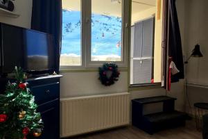 un salon avec un arbre de Noël et une télévision dans l'établissement Le perchoir de Juliette, à La Mongie