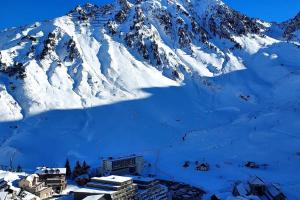una montaña cubierta de nieve con una pequeña ciudad en primer plano en Le perchoir de Juliette, en La Mongie