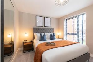 ein Schlafzimmer mit einem großen Bett mit blauen Kissen in der Unterkunft Elliot Oliver - Stylish Loft Style Two Bedroom Apartment With Parking in Gloucester