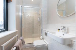 a bathroom with a toilet and a sink and a mirror at Elliot Oliver - Stylish Loft Style Two Bedroom Apartment With Parking in Gloucester