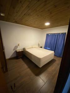 1 dormitorio con cama blanca y cortinas azules en LOS ABUELOS Casa a 50 metros del mar en Mar del Plata