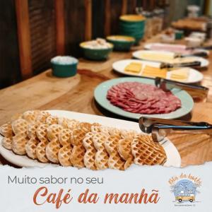 una larga mesa de madera con platos de comida. en Pousada Rota da Kombi en Bom Jardim da Serra